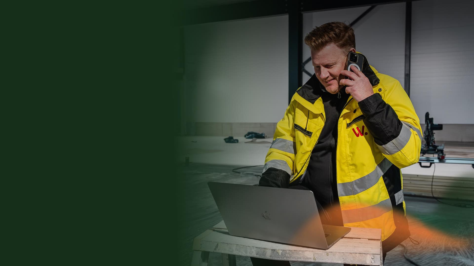Projektledare i byggbranschen som sitter framför dator på byggarbetsplats