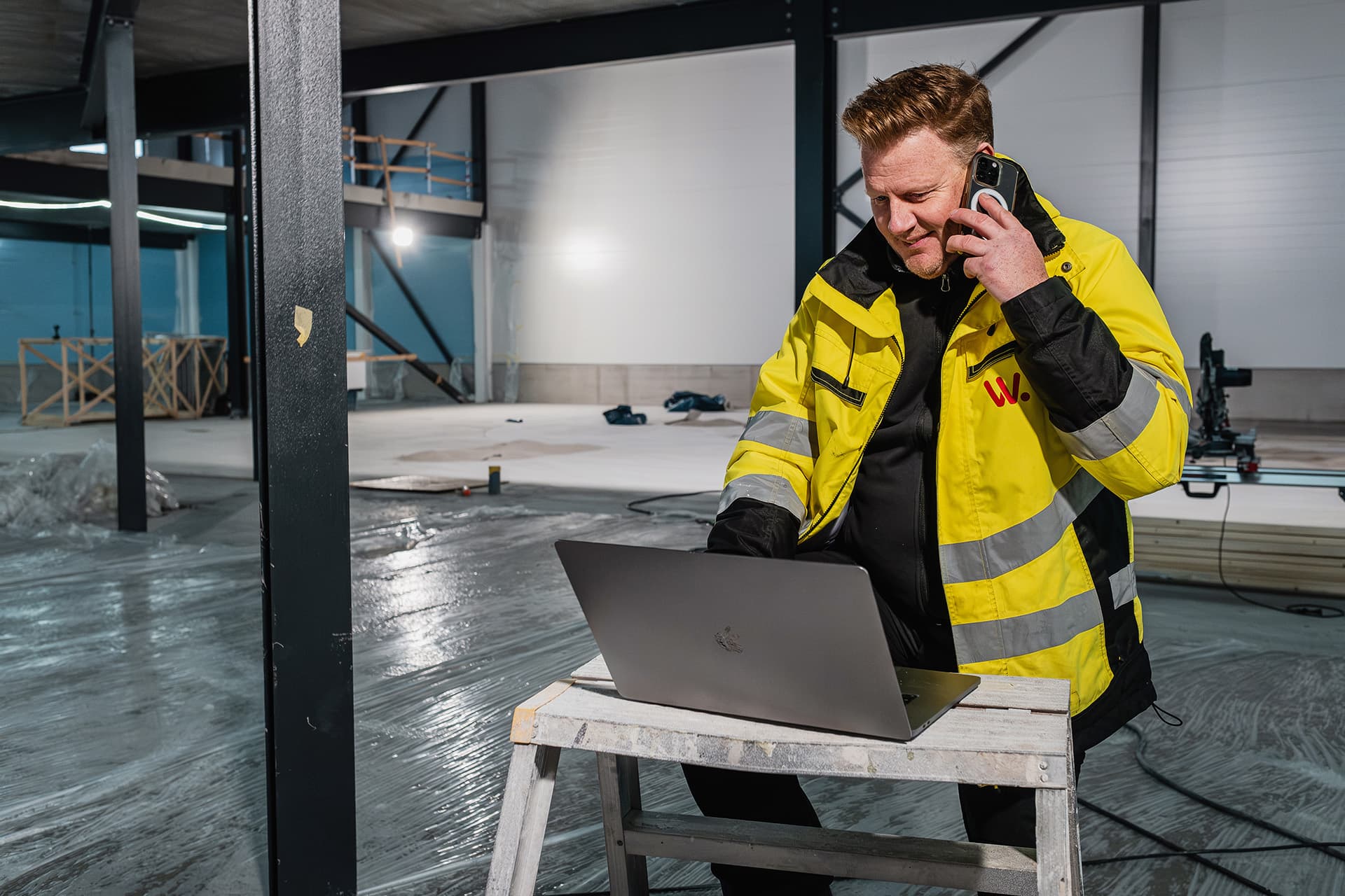 Projektledare i byggbranschen som sitter framför dator på byggarbetsplats